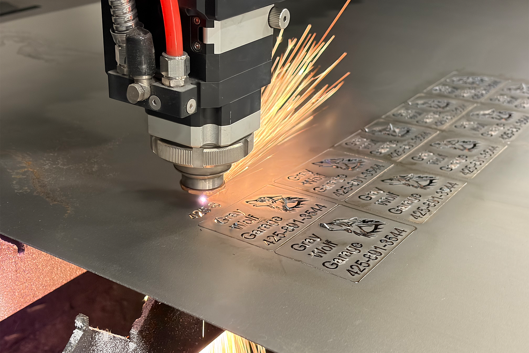 CNC laser head cutting metal business cards with sparks flying