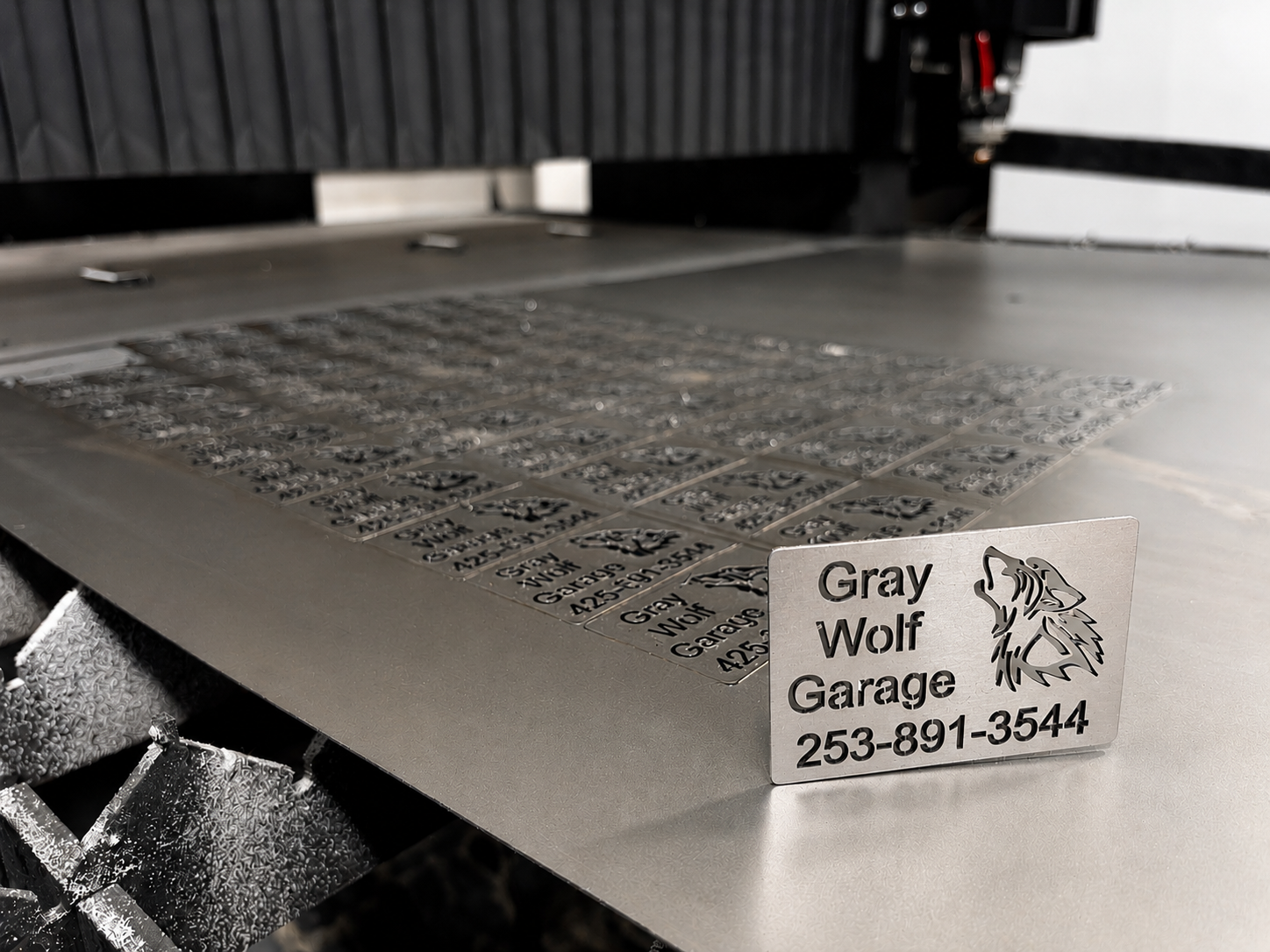 Laser-etched metal business cards with Gray Wolf Garage logo on the cutting table